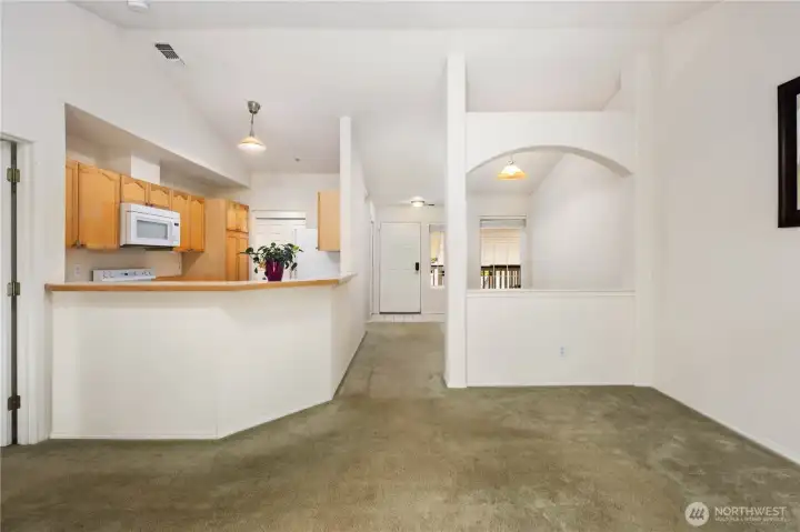 Living & Kitchen Flow: Open concept design connects living, dining, and kitchen spaces, maximizing function and light. Vaulted ceilings enhance the spacious feel of this top-floor unit.
