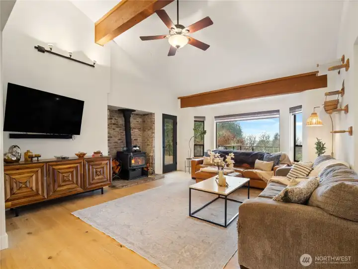 The family room has a cosy wood stove and tall ceilings with solid beam details.