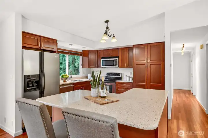 This kitchen delivers great storage and a clean, classic look with wood cabinetry, stainless microwave and range, and wide counters that keep everything within reach. The oversized island offers a true gathering space, ideal for meal prep, appetizers, and casual dining without losing the open connection to the rest of the home. Hardwood flooring ties it all together with warmth and durability.