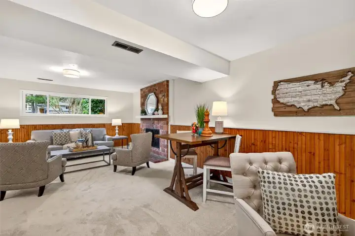 This wide view highlights the true advantage of this lower level, it functions like a second living room with room for both conversation seating and a separate flex zone. The brick fireplace adds timeless charm, while the neutral finishes and updated lighting keep it bright and easy to personalize. Whether you are hosting, streaming a game, or setting up a reading nook, the space adapts beautifully to your lifestyle.