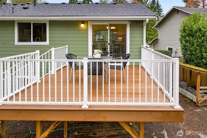 This view shows the easy indoor to outdoor flow, with a sliding door that makes hosting feel seamless and natural. The freshly finished deck surface and bright white railings create a clean, inviting outdoor room that feels elevated and usable year round. Add a grill station and a couple lounge chairs, and you have an effortless entertaining setup right off the main living spaces.