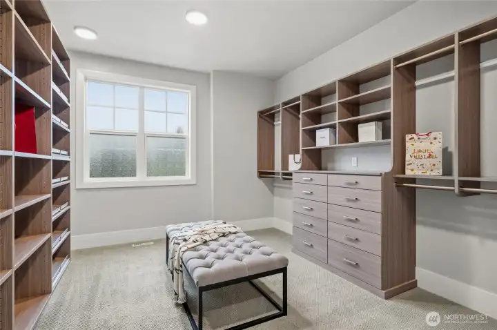 Generous walk-in closet with custom built-in shelving.