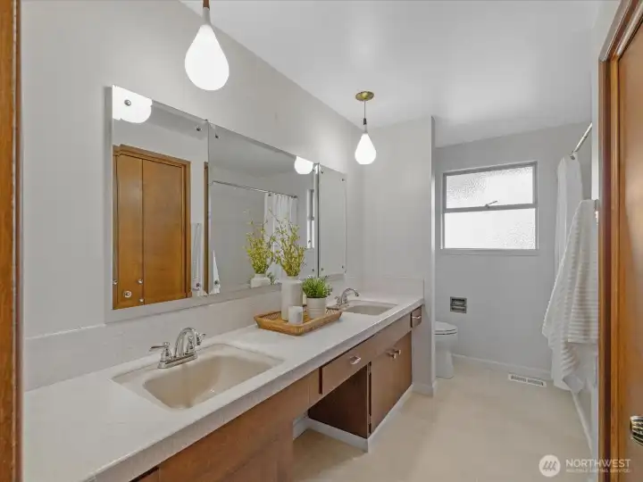 The main bath with its dual sink vanity. The counters and tub surround are tiled and there is a large linen closet.