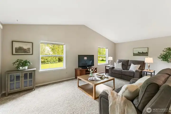 A grand size family room with views of a mountain backdrop and the beautifully landscaped grounds.