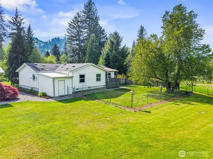Looking at the rear of the home and the fully fenced yard area for pets. A storage room provides even more space.