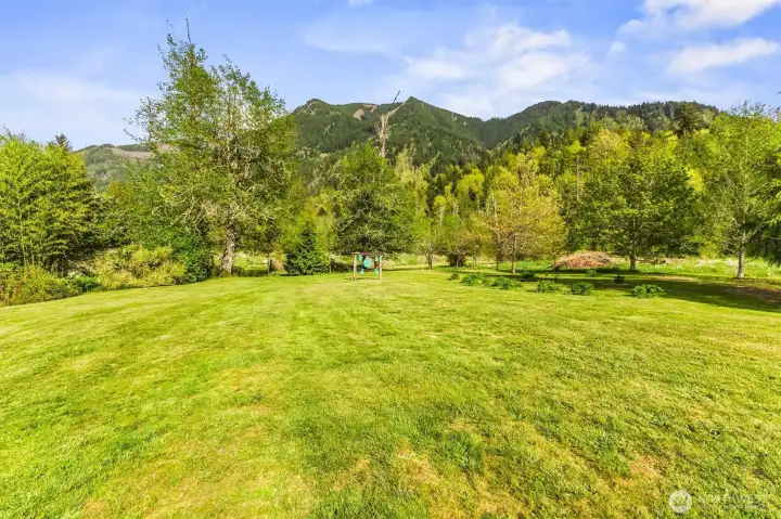 An expansive open grassy area framed by a stunning mountain backdrop.