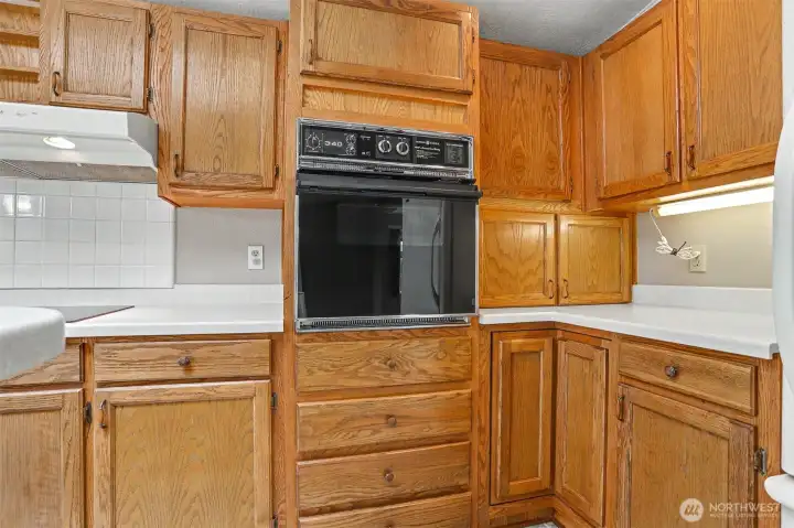 Gourmet kitchen features a center island, quartz counters, skylight, oak cabinets, wall oven, cooktop and a eating nook overlooking the community greenbelt.