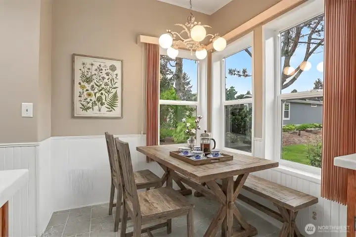 Gourmet kitchen features a center island, quartz counters, skylight, oak cabinets, wall oven, cooktop and a eating nook overlooking the community greenbelt.  Virtually staged photo.