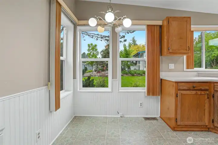 Gourmet kitchen features a center island, quartz counters, skylight, oak cabinets, wall oven, cooktop and a eating nook overlooking the community greenbelt.