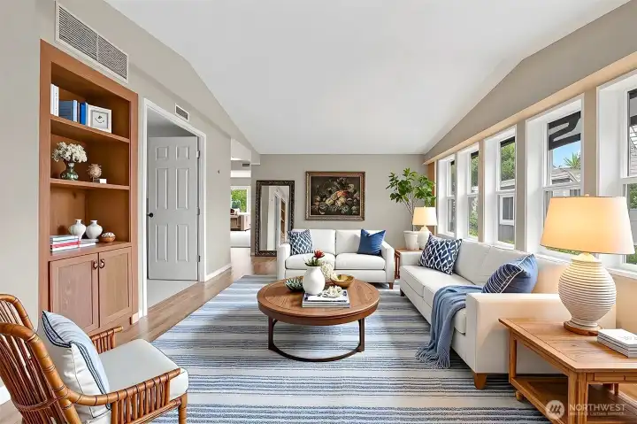 Formal living room has vaulted ceilings, laminate floors and opens to the office/den/bonus room.   Virtually staged photo.