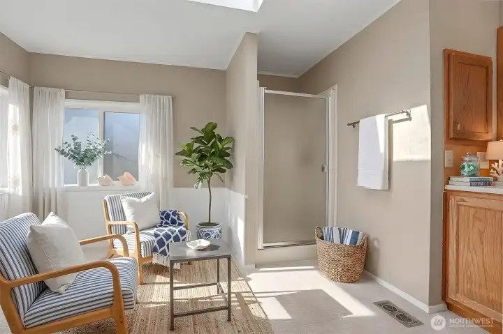 Master bedroom suite with vaulted ceilings, sliding door to light and bright south facing deck and a 3/4 bathroom.  Virtually staged photo.