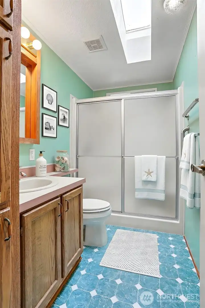 2nd bathroom with a skylight, walk in shower and oak cabinets.  Virtually staged photo.