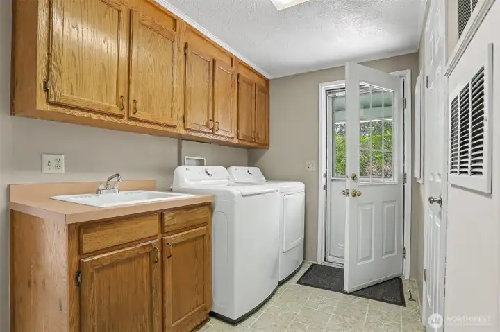 Utility room with included full size washer and dryer, sink and space for a 2nd refrigerator/freezer.  Opens to the back patio.