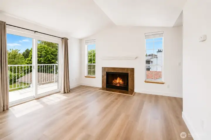 The sunny and spacious living room features vaulted ceilings and a cozy fireplace.