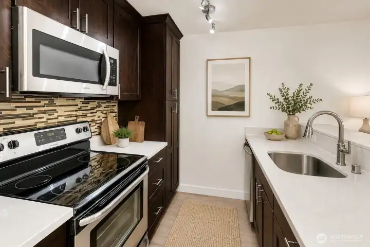 The upgraded galley kitchen features quartz countertops, a breakfast bar, stainless steel appliances.