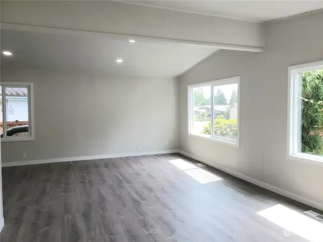 Huge Living Room Area with All New Painted Walls, Cathedral Ceiling, Trim, New Vinyl Windows, Vinyl Plank Flooring Looking from the Front Door Entry to the Front Covered Front Porch.