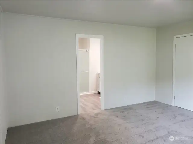 Another View of the Spacious Primary Master Bedroom with Brand New Carpet, Paint, Showing Entry to the Bathroom and the Entry Bedroom Door.