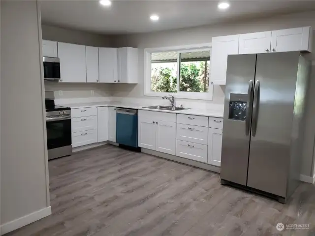 Huge Open Kitchen with All New White Cabinets, Counter Tops, Double Sink, Faucet, Stainless Appliances and Vinyl Plank Flooring.