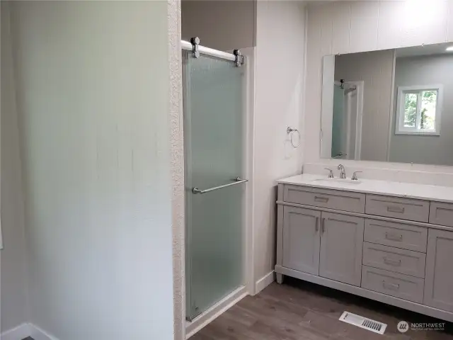 Another Picture of the roomy Primary Master Bathroom Showing All New Cabinet Vanity, Counter Top, 2 Sinks, Faucets, New Walk In Shower, Paint and Vinyl Plank Flooring.