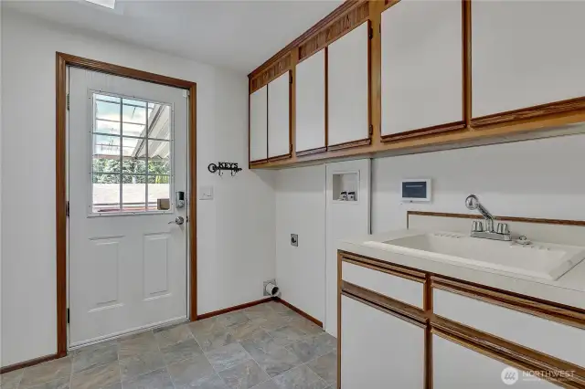 Convenient laundry room with utility sink, extra cabinet space, and access to the covered carport.