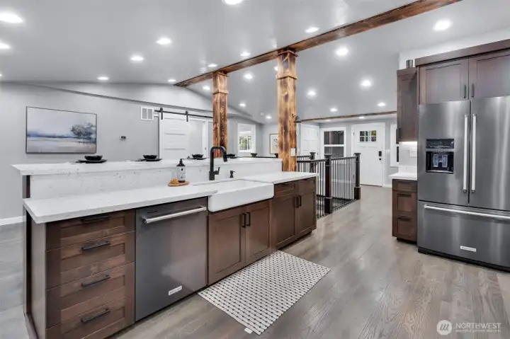 Large, oversized center island offers bar counter seating, built in white cast iron farm sink with goose neck faucet, storage and dishwasher.