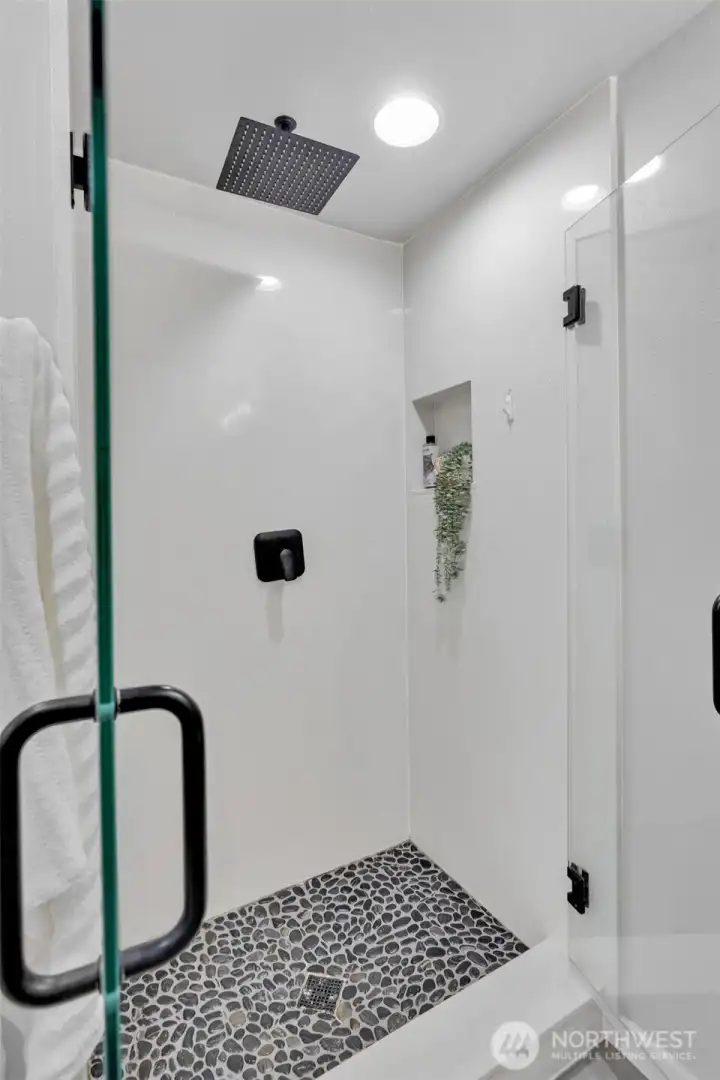 Large walk-in shower with seamless glass doors and custom tile work.