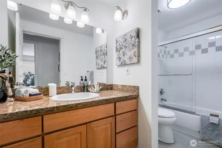 Bathroom with granite countertops and bathtub/shower.