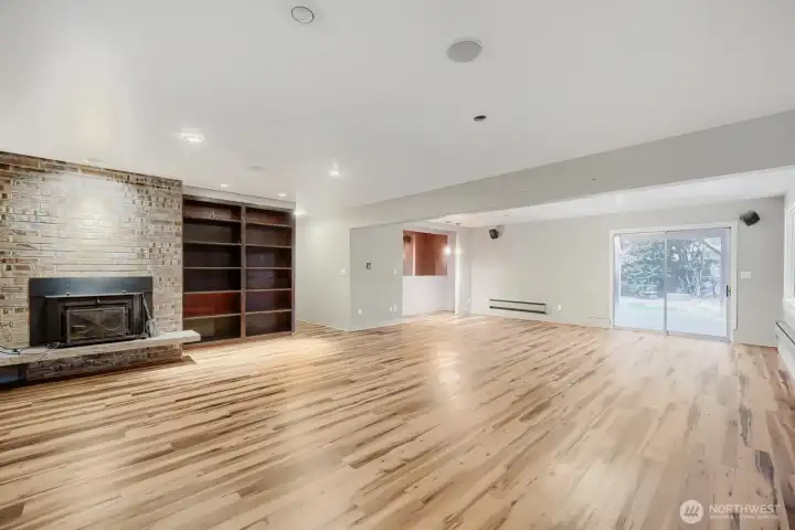 Lower-level rec room with a wood-burning fireplace; sliding glass doors lead to the lower-level patio and yard.