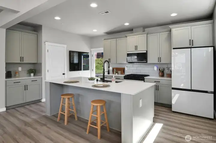 Modern kitchen with large center island, subway backsplash, and walk-in pantry.