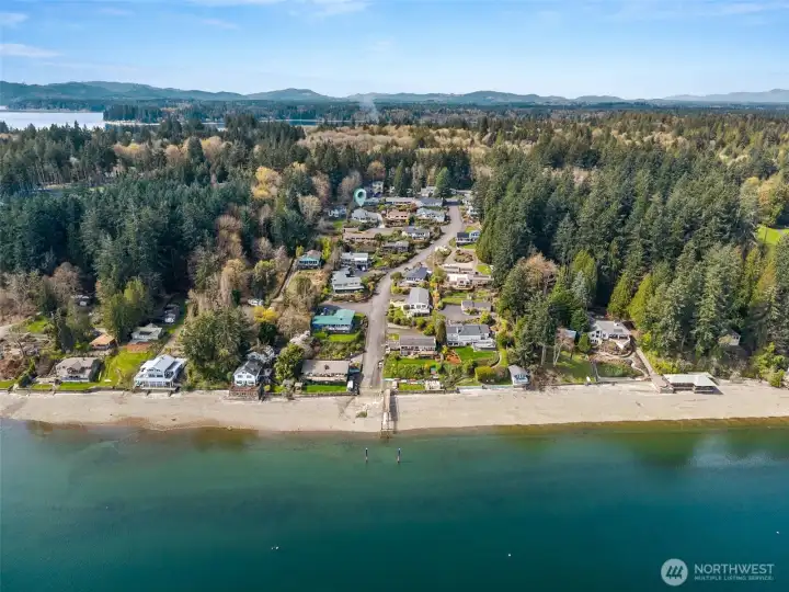 From the front approach, you’re already looking out over the water, with Mount Rainier making a stunning appearance in the distance on clear days, a view that carries through to the interior and deck as well. The driveway layout is easy to navigate, with enough space for a comfortable turn-around instead of backing out blindly. You can also see the side entry into the garage with its own covered overhang, a small but practical detail for everyday use. The private beach and dock sit at the base of Beverly Beach as it winds up through a neighborhood filled with mature evergreens and well-kept homes, creating that tucked-away, established feel people are always looking for. You can spot the home marked along the hillside, perfectly positioned to take in the surroundings. There’s a sense of history here, years of gatherings, beach days, and quiet evenings that give the area a really good, lived-in vibe. Beyond the neighborhood, the location keeps things convenient to   Westside amenities.