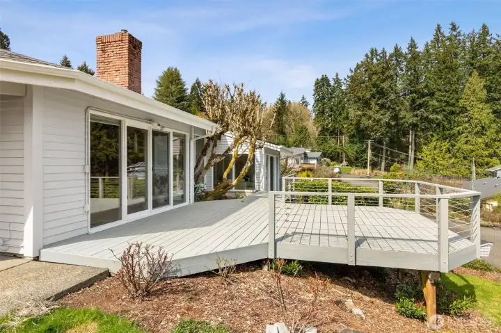 Up on the deck, everything opens up a bit more. The wood and cable railing keeps the lines clean and the view unobstructed, so your eye moves right through to the surrounding greenery and beyond. The sliding doors back to the family room make it easy to go in and out, which is exactly what you want when this becomes your go-to hangout spot. From here, you also get a sense of the home’s elevation, sitting slightly above the properties behind, which adds a bit of privacy and a wider outlook.