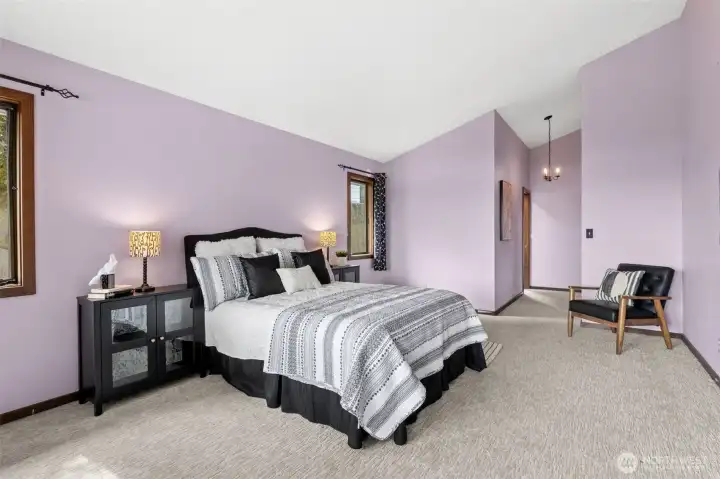 Windows on either side of the bed keep the space bright and connected to the outdoors, while still feeling calm and private. The transition toward the ensuite is easy and intuitive, with a hallway that feels integrated into the room’s design. Overhead, a chandelier adds a bit of character, bringing in that subtle vintage touch that ties back to the home’s original era without feeling out of place.