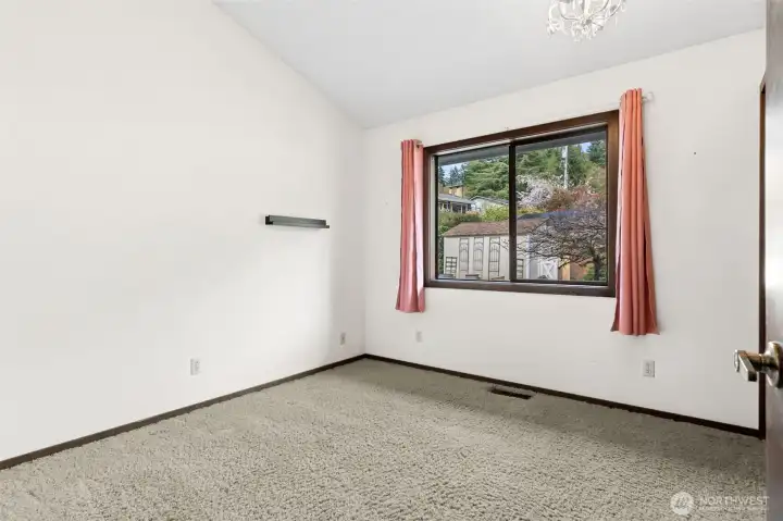 Bright, simple, and surprisingly private, this 3rd bedroom makes great use of its space. The vaulted ceiling lifts the room and keeps it from feeling boxed in, while the large picture window brings in natural light and a view of the front yard. Clean white walls give it a fresh, open feel, and the soft carpeting keeps it comfortable underfoot. A standout detail here is the dual closets, which is always a win for storage. And one of the more thoughtful features of this home overall, none of the bedroom walls line up with each other, creating a natural buffer for added privacy that you don’t often see.