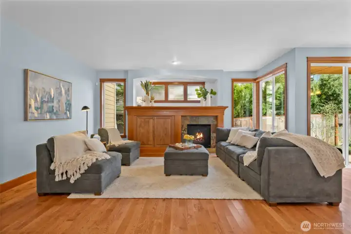 Light-filled living room has a gas fireplace with a timeless mantel, complemented by refined millwork cabinetry and ample windows that create an airy, elegant ambiance.