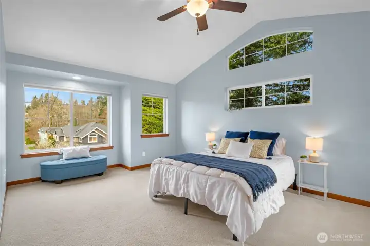 Spacious second upstairs bedroom filled with natural light from surrounding windows, with convenient access to an adjoining full bathroom.