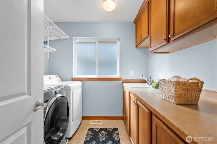 Well-appointed laundry room on upper level featuring a sink and plenty of cabinetry for ample storage.