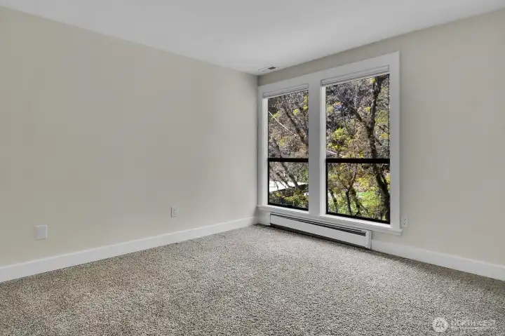 And the third bedroom on the upper floor offers a treetop view through a large, leafy maple.