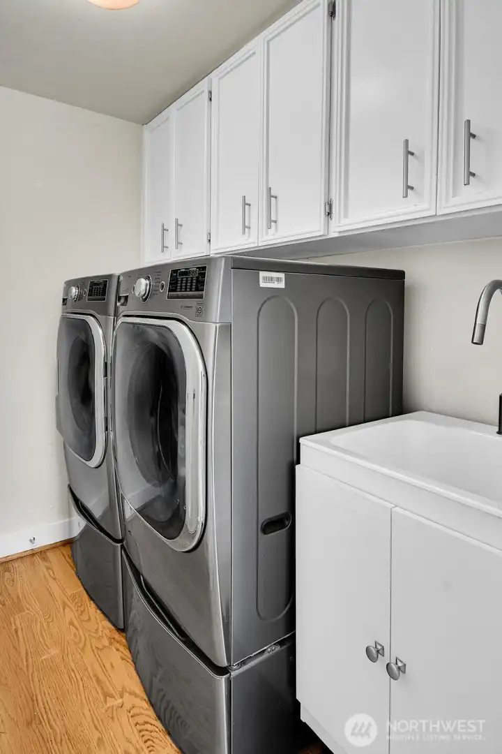 The utility room includes a stainless, front-loading washer & dryer, a utility sink, plus plenty of storage.