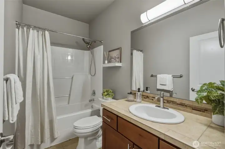 Full bathroom with tile countertops and a tub/shower combination.