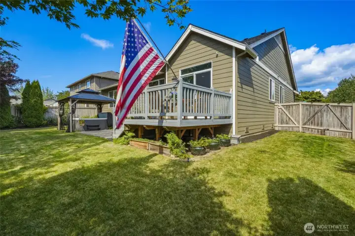 Fully fenced backyard with a spacious deck, patio, gazebo, and lush lawn