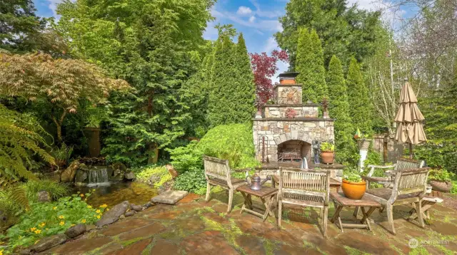 Outdoor fireplace positioned next to a babbling brook.