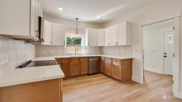 New kitchen with modern two-toned cabinetry, gorgeous counters and stainless appliances.