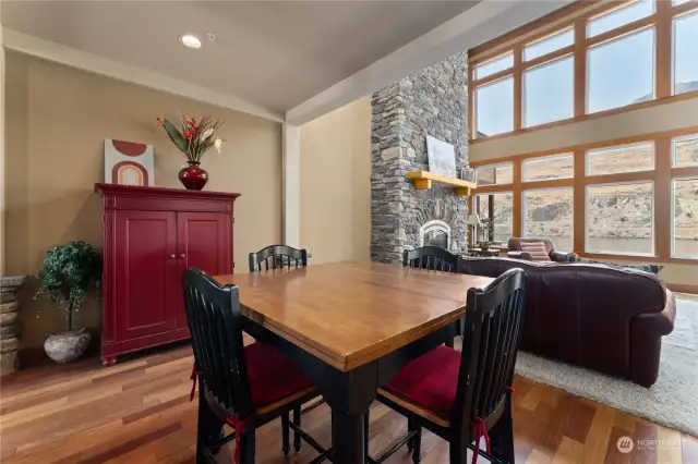 View 1 of living room w/ bonus dining area, stone fireplace, vaulted ceilings, oversized windows and glass sliding doors leading to the waterfront view deck and outdoor living area.