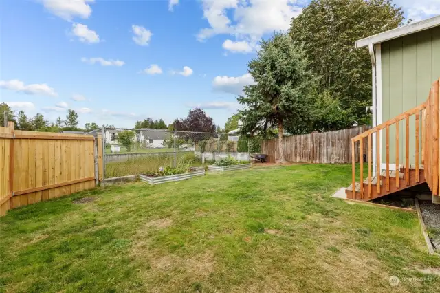 Back yard view. Raised veggie garden beds with a yard providing room to work, garden, & play!