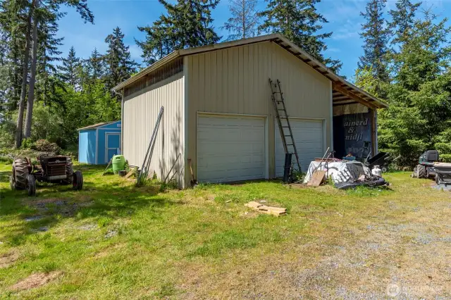 The two car garage with a carport and one of five sheds in the back.