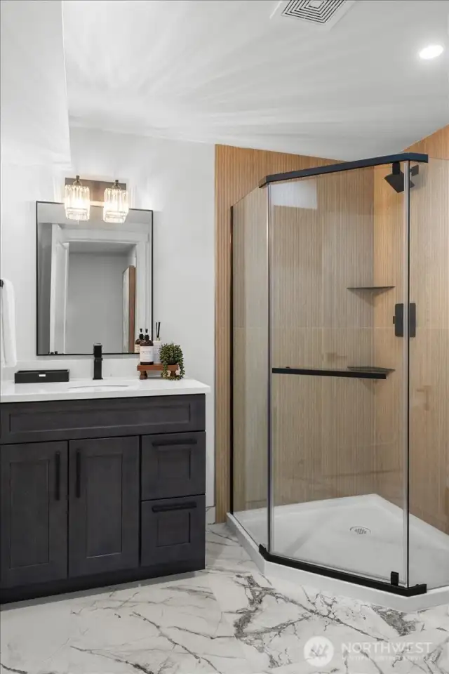 Downstairs bathroom with quartz countertops, large corner shower with custom tile and beautiful tile flooring.