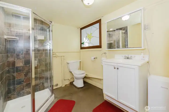 Downstairs bathroom with tiled shower stall and pretty stained glass for natural light from laundry room.