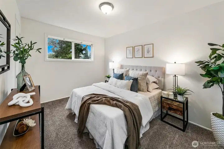 A comfortable main-level bedroom with south-facing windows overlooking the private backyard, filling the space with natural light throughout the day.