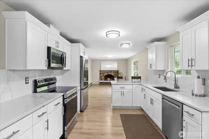 Classically updated kitchen in 2023 features beautiful white cabinetry, stunning quartz countertops, and an incredible matching quartz backsplash, creating a sense of continuity. Stainless steel appliances are just three years old.
