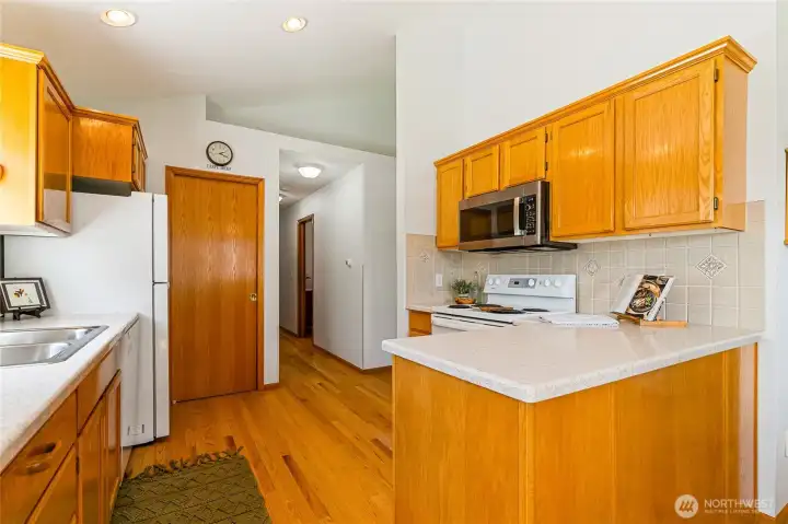 Corian counters and Italian handmade marble backsplash elevate this roomy kitchen. Looking down the hallway leads you to an additional 3/4 bath to the left and primary bedroom to the right. Behing the kitchen is the living room. Corian counters and Italian handmade marble backsplash elevate this roomy kitchen. Looking down the hallway leads you to an additional 3/4 bath to the left and primary bedroom to the right. Behing the kitchen is the living room.